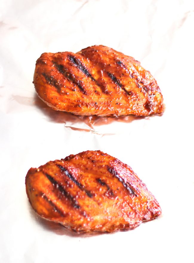 Two pan-grilled and oven baked Bulgogi chicken breasts on a sheet of foil before slicing