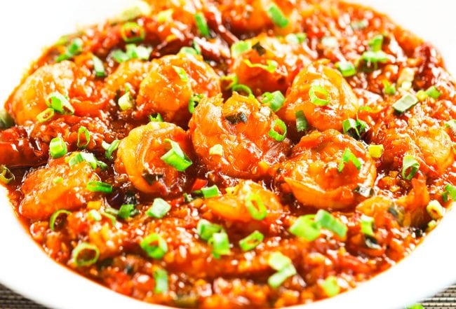 Chili Garlic Shrimp garnished with freshly chopped spring onion greens in a deep white plate.