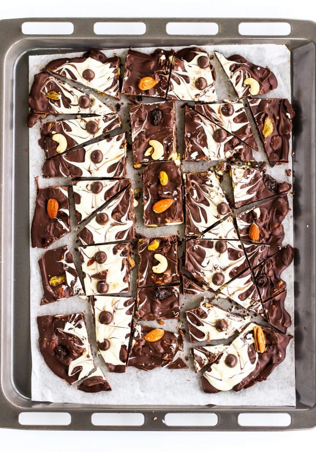Dark and white chocolate bark (pieces) with mixed dried fruits and nuts and McVities Dark Chocolate Nibbles on top of a nonstick cooking paper layered on a large baking tray.