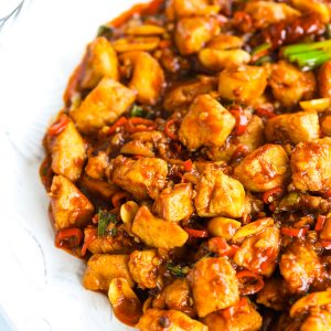 Kung Pao Chicken on a white plate that is cut off from the frame on the right side.