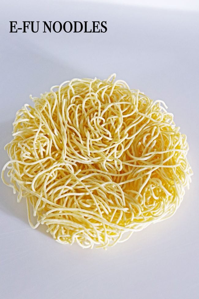 Uncooked round disc of yellow e-fu noodles.