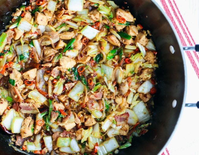 wok with stir-fried chicken, bacon, cabbage, chopped red chillies, and spring onions
