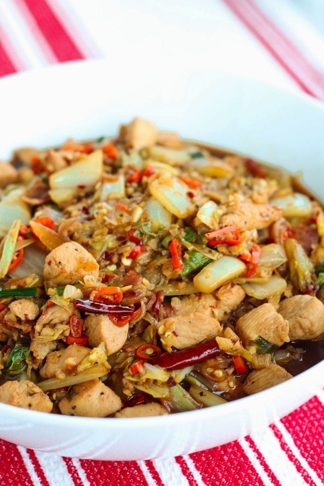 chicken, bacon, cabbage, spring onion, dried red chilies in white round serving bowl