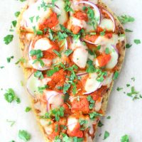 Naan with spicy pizza sauce, chicken tikka pieces, red onion, cheese, and chopped coriander