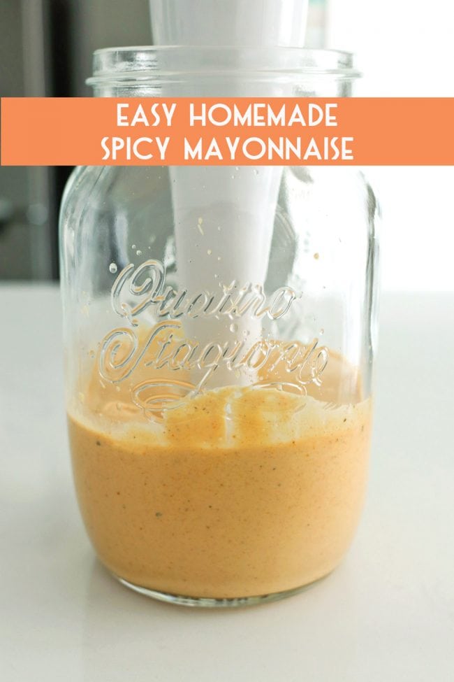 Spicy mayonnaise in a glass jar with a handheld blender immersed inside.