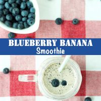 Blueberry banana smoothie in a mason jar mug with a straw and a small white dish with blueberries behind the mug. Blueberry scatter around mug.