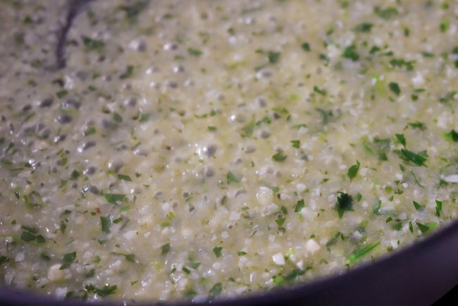 Garlic, onion, and fresh parsley simmering in pan with white wine