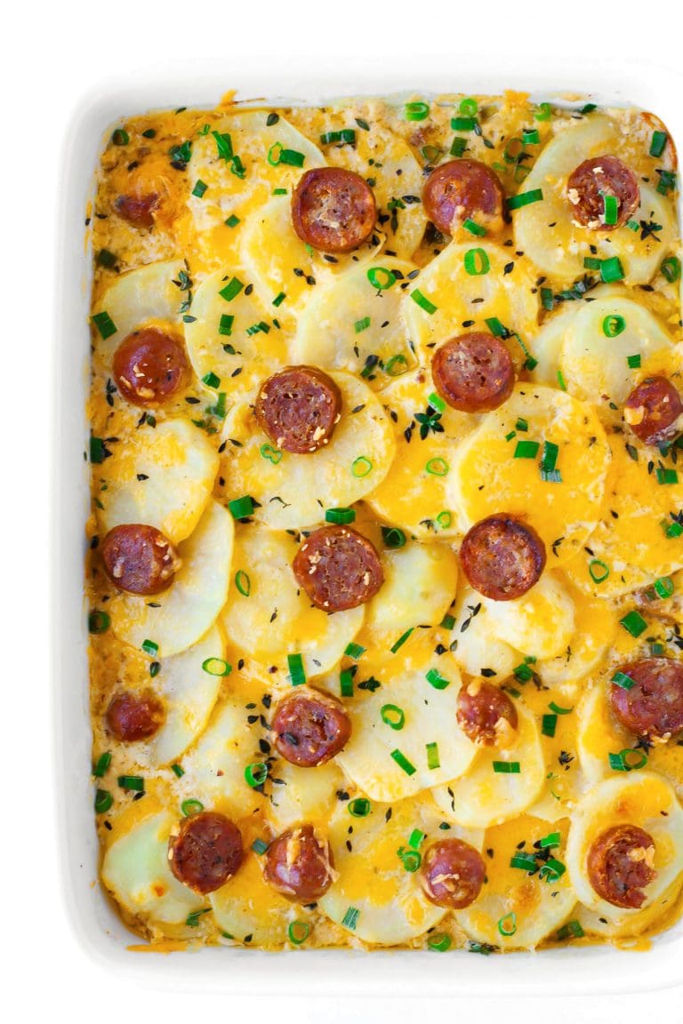 Scalloped potatoes with sausage coins in a large baking dish.