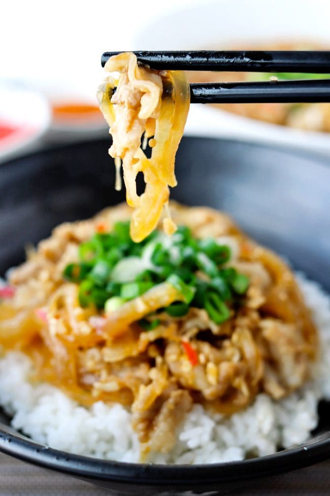 Chopsticks with a piece of pork belly over a Japanese Pork Rice Bowl.