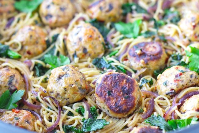Deep large sauté pan with Brown Butter Miso Pasta and Baked Spicy Chicken Meatballs garnished with fresh parsley leaves.
