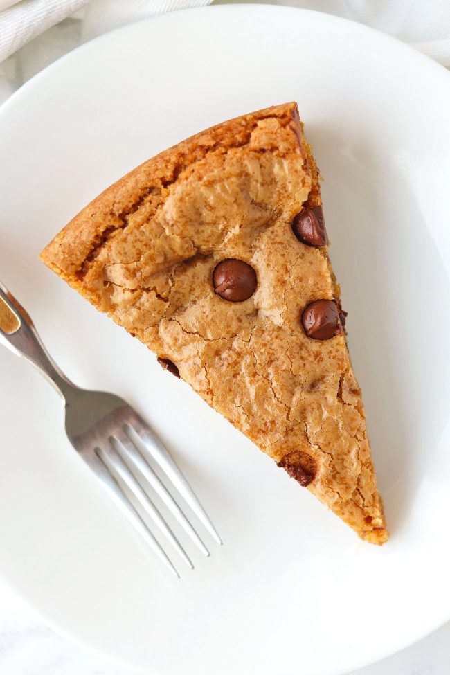 Chocolate Chip & Butterscotch Chip Cookie Cake slice on a white round plate with a fork next to it.
