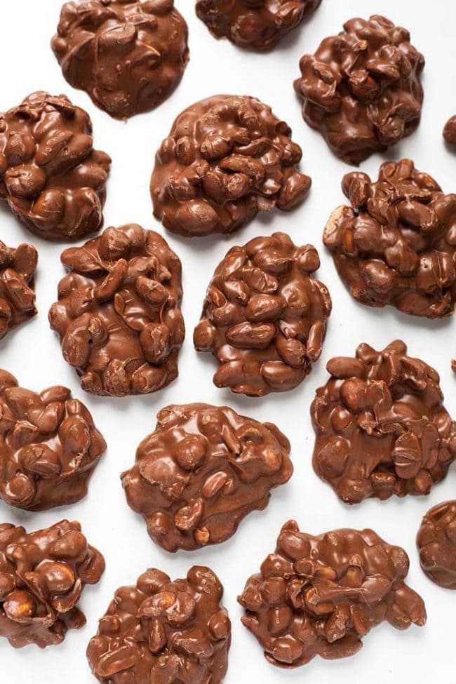 Chocolate Peanut Clusters spread out on a white background.