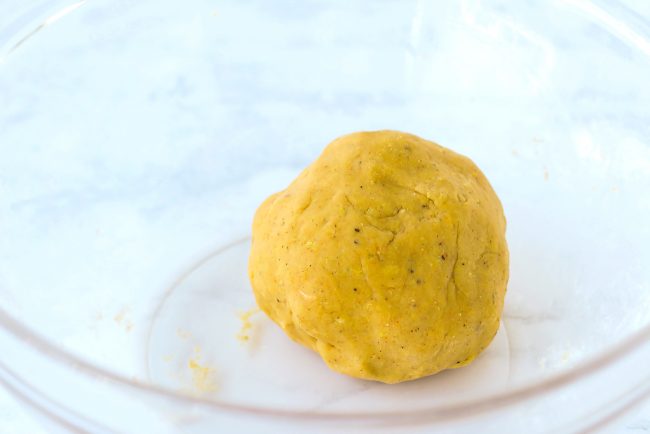 Yellow dough shaped in a ball inside a large mixing bowl.