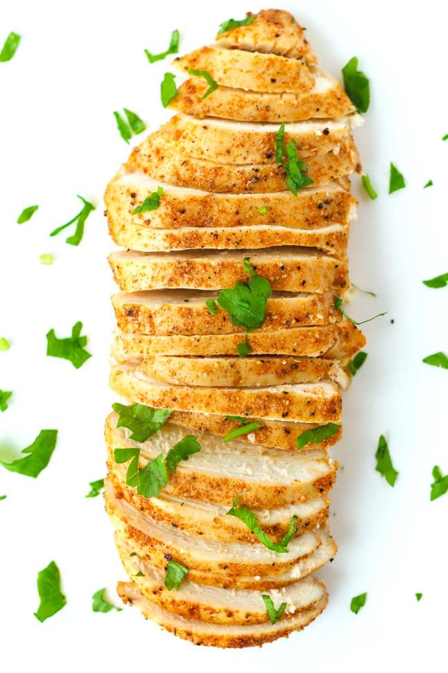 Thinly sliced seasoned and baked chicken breast garnished with chopped fresh parsley.