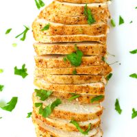 Thinly sliced seasoned and baked chicken breast garnished with fresh chopped parsley.