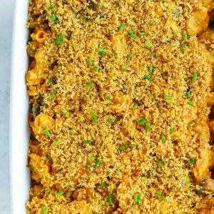 Top view of harissa mac and cheese in a large baking dish with a breadcrumbs topping and chopped chives garnish.
