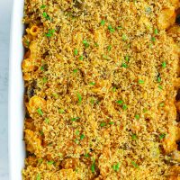 Top view of harissa mac and cheese in a large baking dish with a breadcrumbs topping and chopped chives garnish.