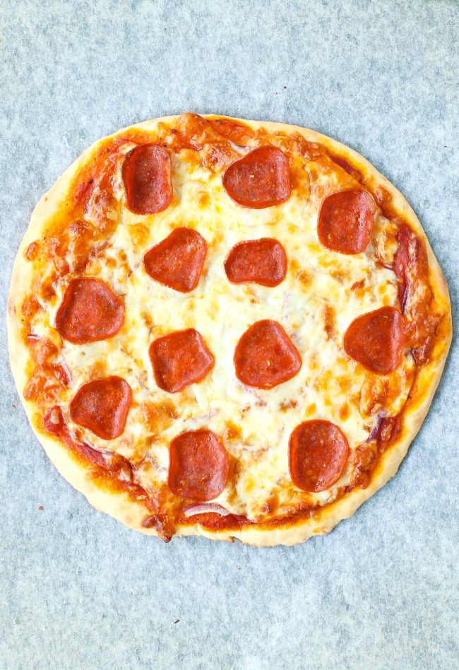 A freshly baked whole pepperoni pizza on parchment paper.