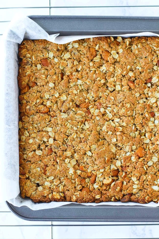 Baked apricot and almond oat mixture in baking pan on top of cooling rack.