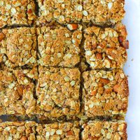 Apricot almond square shaped oat slices on parchment paper.
