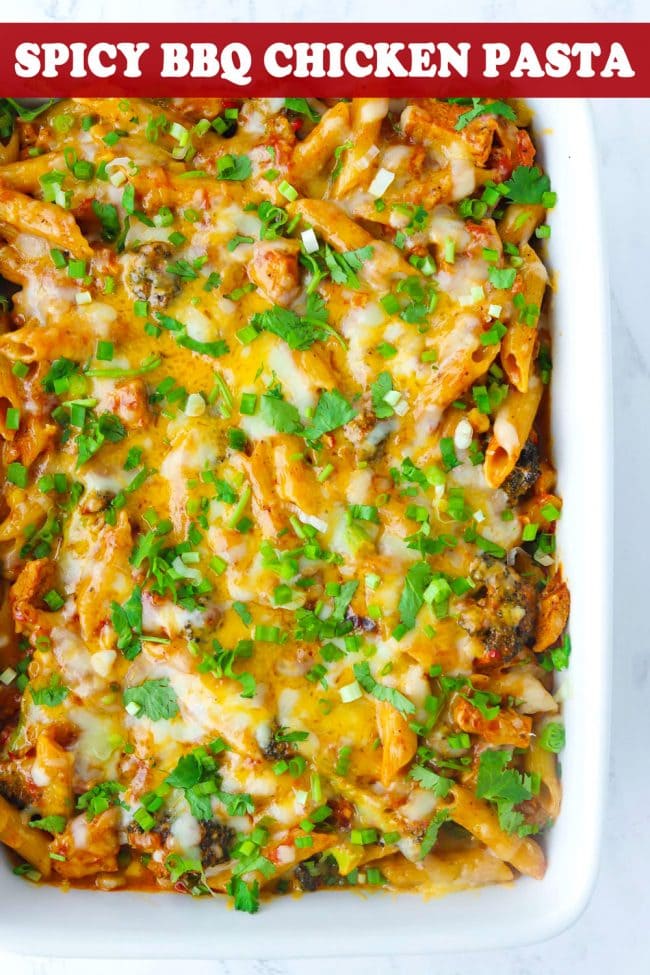 A large baking dish with Spicy BBQ Chicken Penne Pasta with corn, broccoli, melted cheese, and garnished with chopped coriander and spring onion.