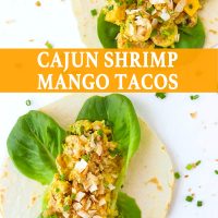 Two open-faced Cajun Shrimp Mango Tacos with butter lettuce and topped with toasted coconut flakes on a white background. Spring onion and coconut flakes scattered around the tacos.
