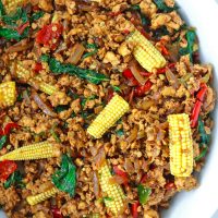 Ground chicken Thai basil stir-fry with sliced baby corn in a large white serving bowl.