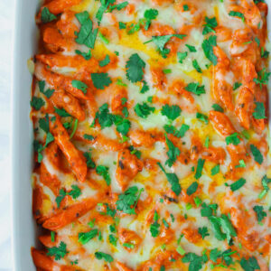 Overhead view of Butter Chicken Pasta Bake garnished with chopped coriander in a baking dish.