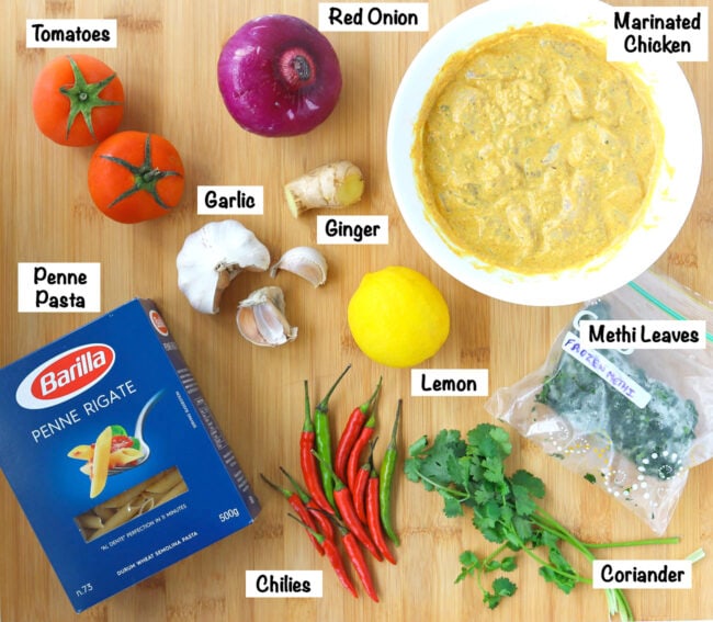 Labeled photo of ingredients for Butter Chicken Pasta Bake on wooden board.