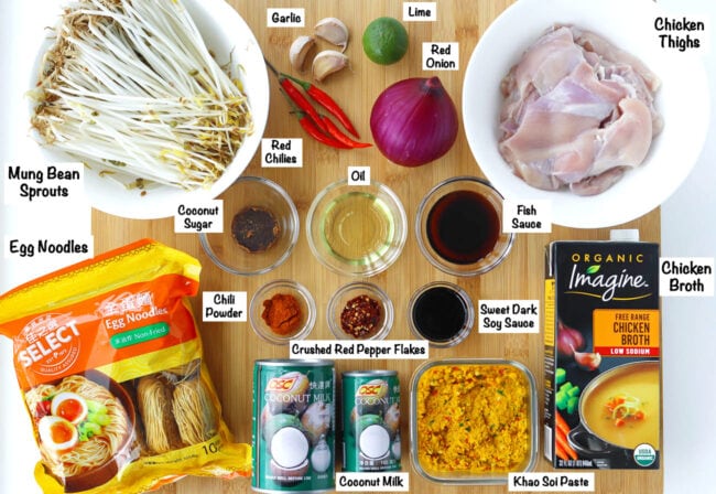 Labeled photo of ingredients for Khao Soi Gai on wooden board.