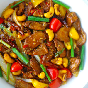 Stir-fry chicken dish with bell peppers and cashews in a round serving bowl.