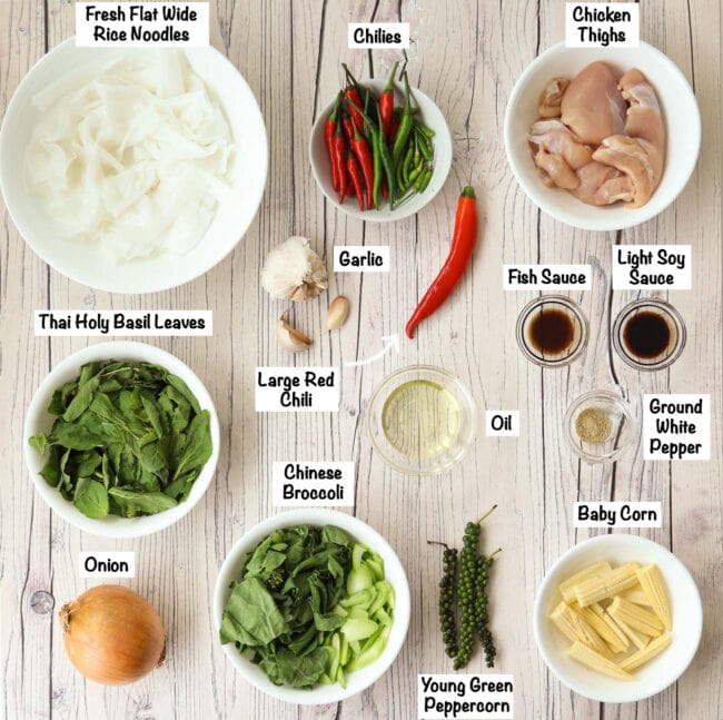 Labeled ingredients to make Pad Kee Mao Gai on wooden background.