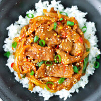 Close-up top view of bowl with spicy pork stir-fry on rice. Text overlay "Spicy Korean Pork Stir-fry".