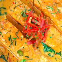 Top close-up view of Thai salmon curry in a white round serving bowl. Text overlay "Choo Chee Salmon Curry" and "thatspicychick.com".