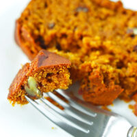 Fork with a bite of bread on a plate with a slice behind. Text overlay "Pumpkin Pecan Bread" and "thatspicychick.com".