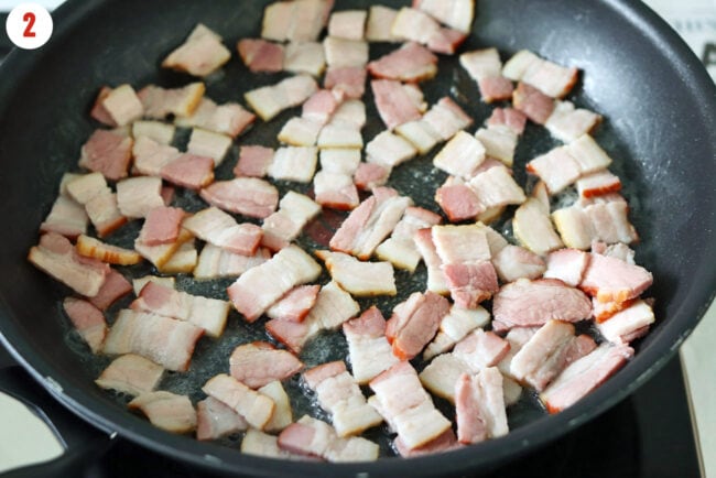 Frying bacon pieces in a skillet on the stovetop.