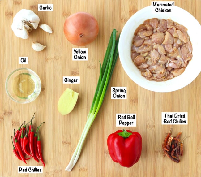 Fresh ingredients for Spicy Pepper Chicken on a wooden board.