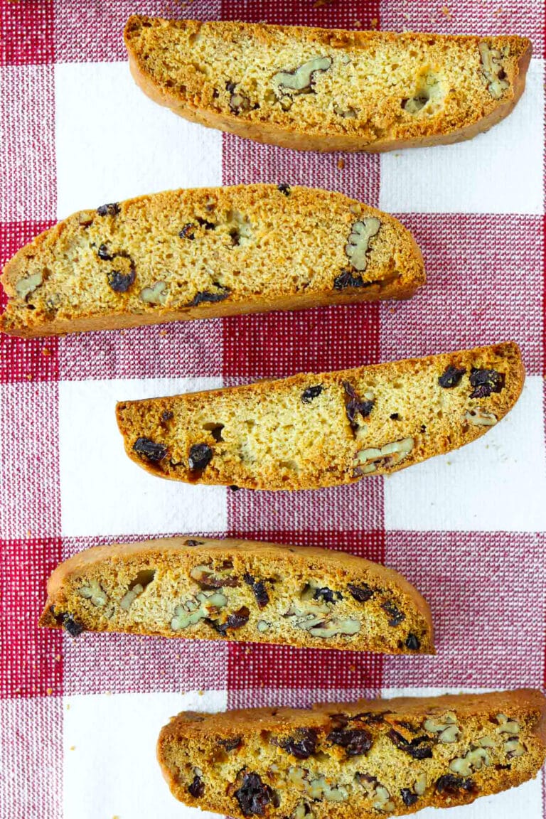 Cranberry pecan biscotti lined up on a red and white checkered napkin.