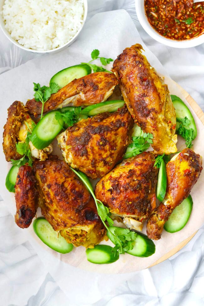 Spicy Thai Roast Chicken pieces on platter with with cucumber slices and coriander sprigs.