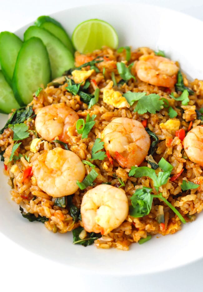 Front view of plate with spicy prawn fried rice with cucumber slices and a lime wedge.