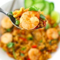 Spoon holding up a bite of spicy fried rice and a prawn. Text overlay "Thai Roasted Chili Fried Rice with Prawns" and "thatspicychick.com".
