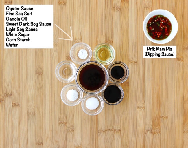 Labeled sauce and seasoning ingredients for Spicy Thai Basil Wontons on a wooden board.