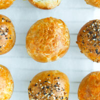 Close-up top view of stuffed baked bagel bombs lined up on nonstick cooking paper.