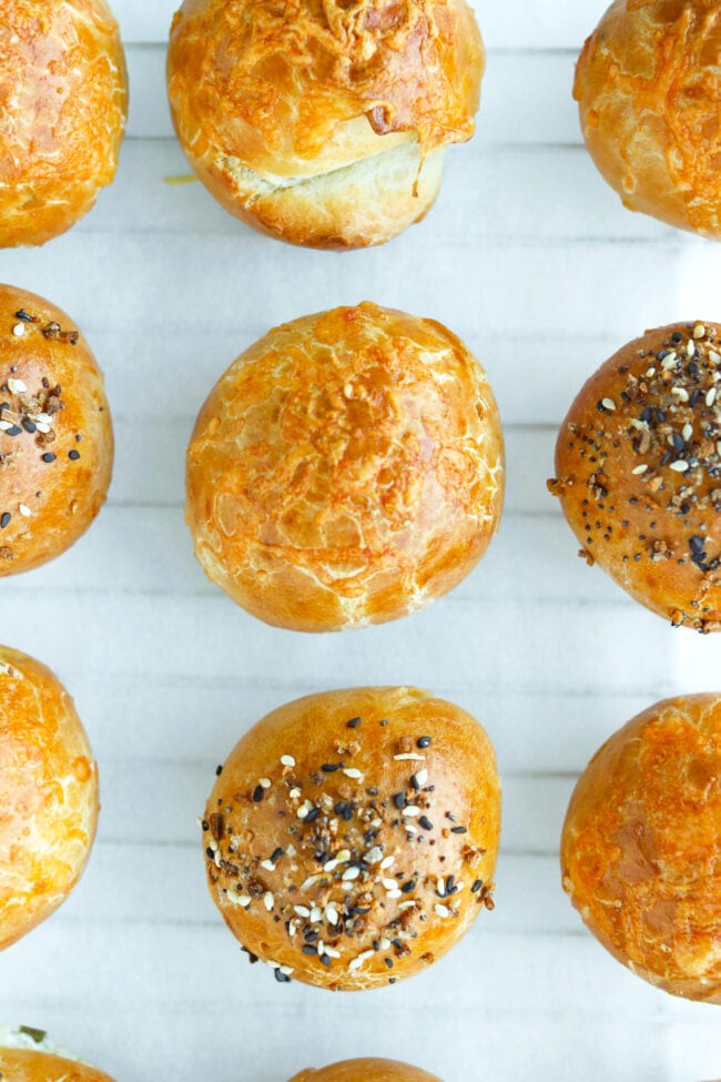 Close-up top view of stuffed baked bagel bombs lined up on nonstick cooking paper.