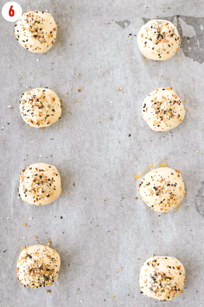 Top view of unbaked bagel balls topped with Everything Bagel Seasoning on parchment paper.