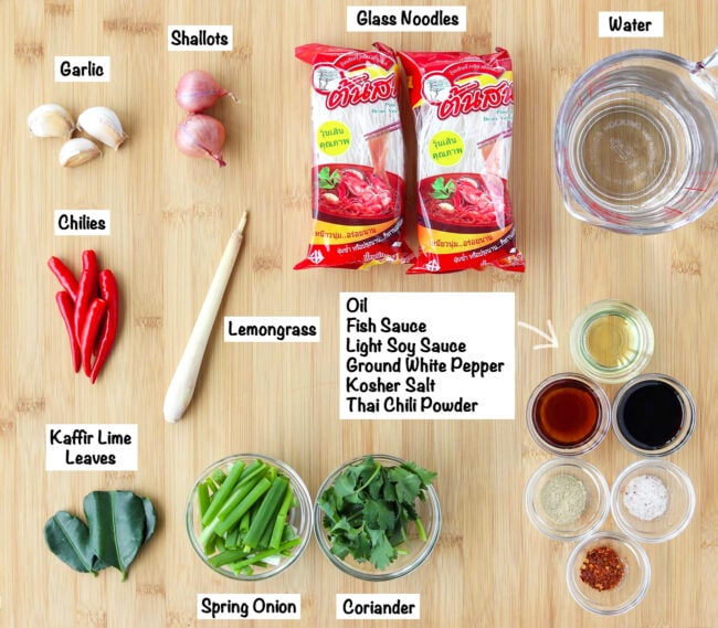 Labeled ingredients for Thai glass noodle soup on a wooden board.