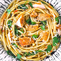 Top view of a plate with salmon pasta. Text overlay "Salmon Pasta with Anchovy-Garlic Sauce" and "thatspicychick.com".