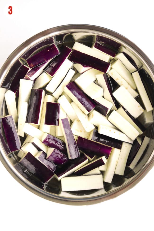 Eggplant strips soaking in a bowl filled with water.