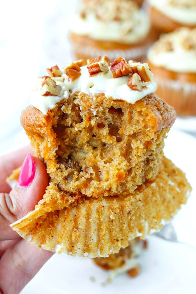 Hand holding up a muffin with a bite out to show the inside.