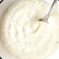 close-up of garlic sauce in bowl with spoon. Text overlay "Easy Kebab Garlic Sauce" "With Mayo and Yogurt", and "thatspicychick.com".